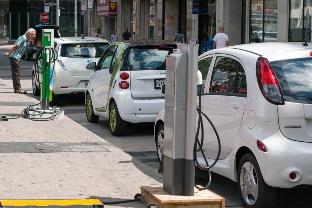 Three electric vehicles parked at curbside charging stations.